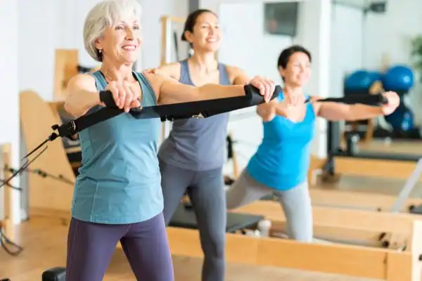 Toning Arms After 60: Empowering Womens Fitness Through Effective Weight Training 2 older woman doing weight training Birmingham and resistance in the gym to tone upper arms