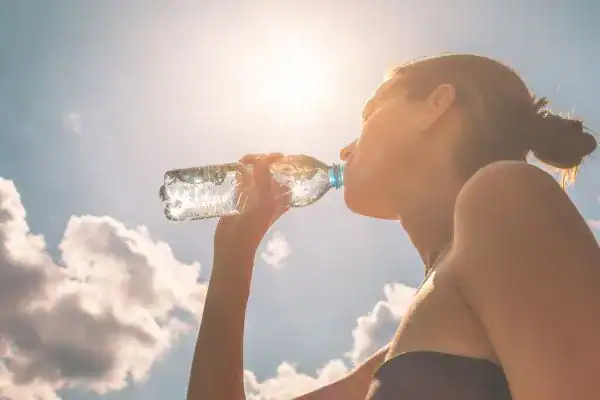 Hydration: The Secret Ingredient for a Toned Stomach and Enhanced Fitness 3 Image of woman drinking water to hydrate Birmingham after run.