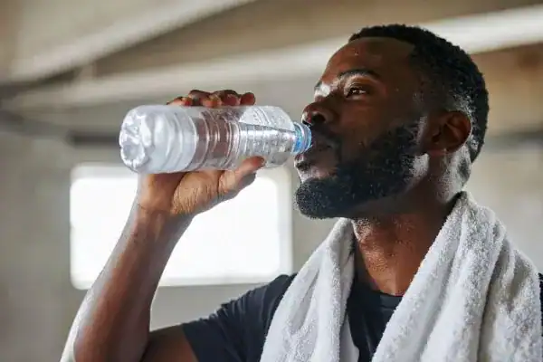 Image of man drinking water to improve hydration Birmingham after work out.